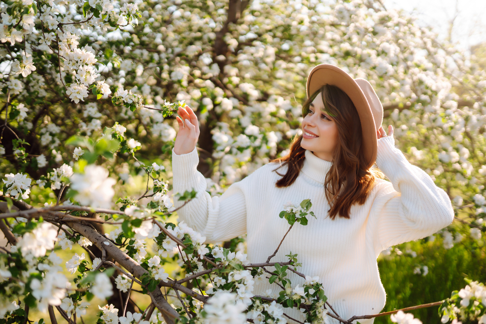 Giovane donna che si gode il profumo in un giardino primaverile in fiore.